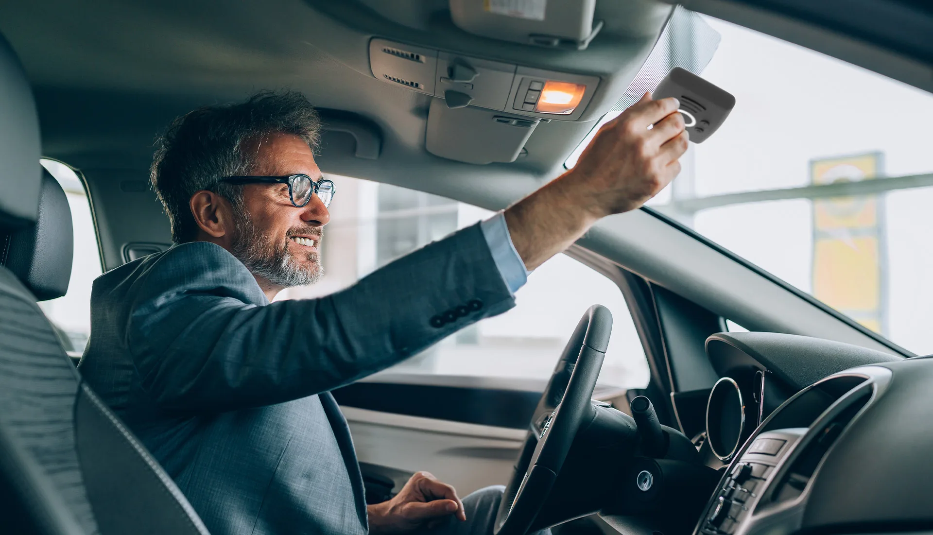 Uomo in giacca che attiva il dispositivo a bordo dell'auto.