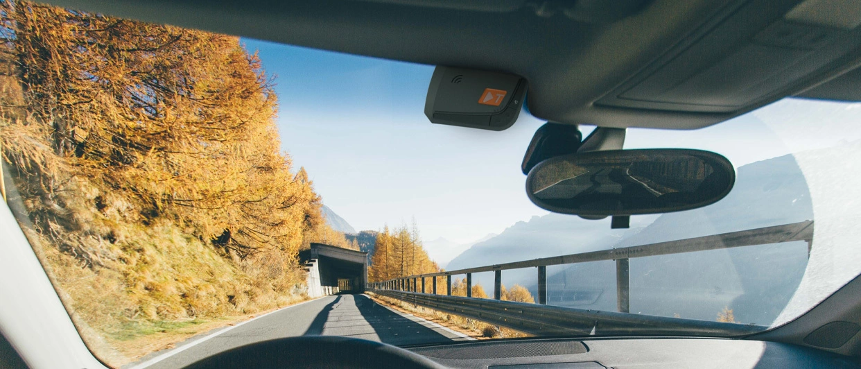 Vista dall’auto su strada di montagna con dispositivo sul parabrezza.