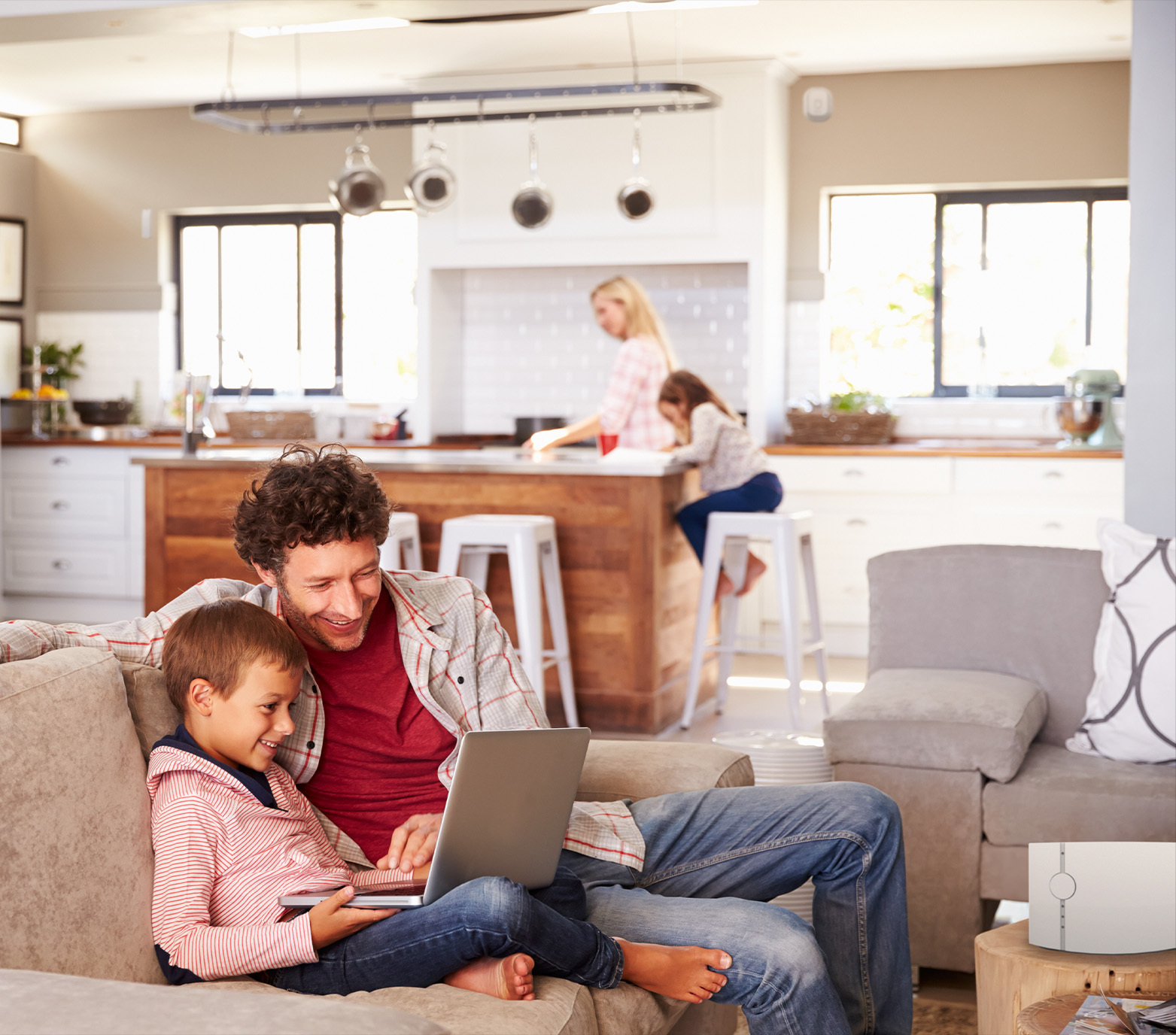 Famiglia in soggiorno con padre e figlio che usano un laptop.