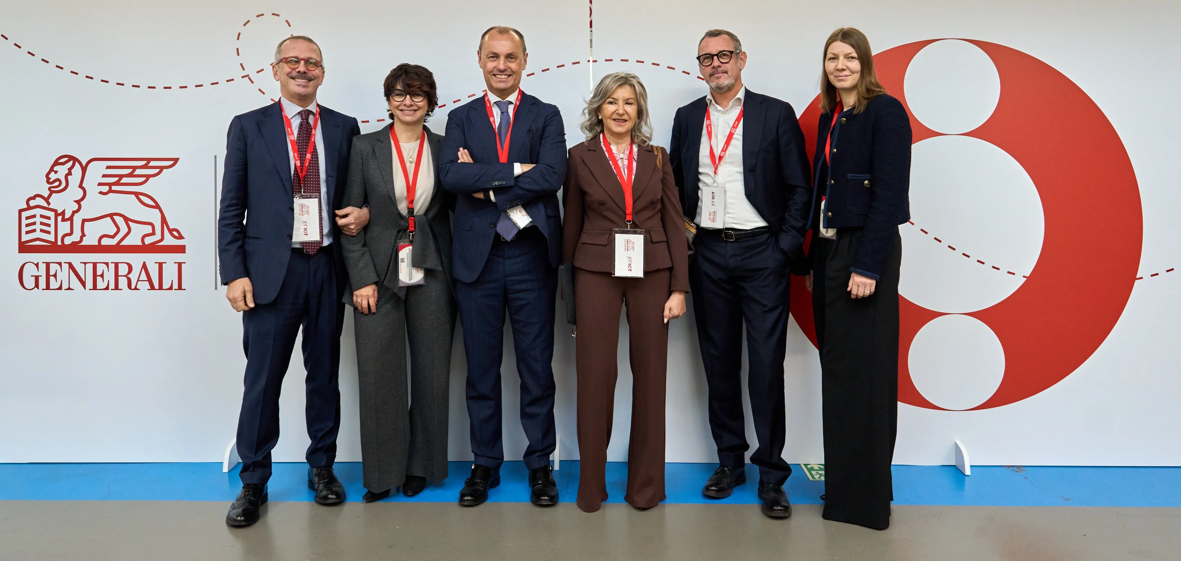 Gruppo di persone con badge davanti al logo Generali.