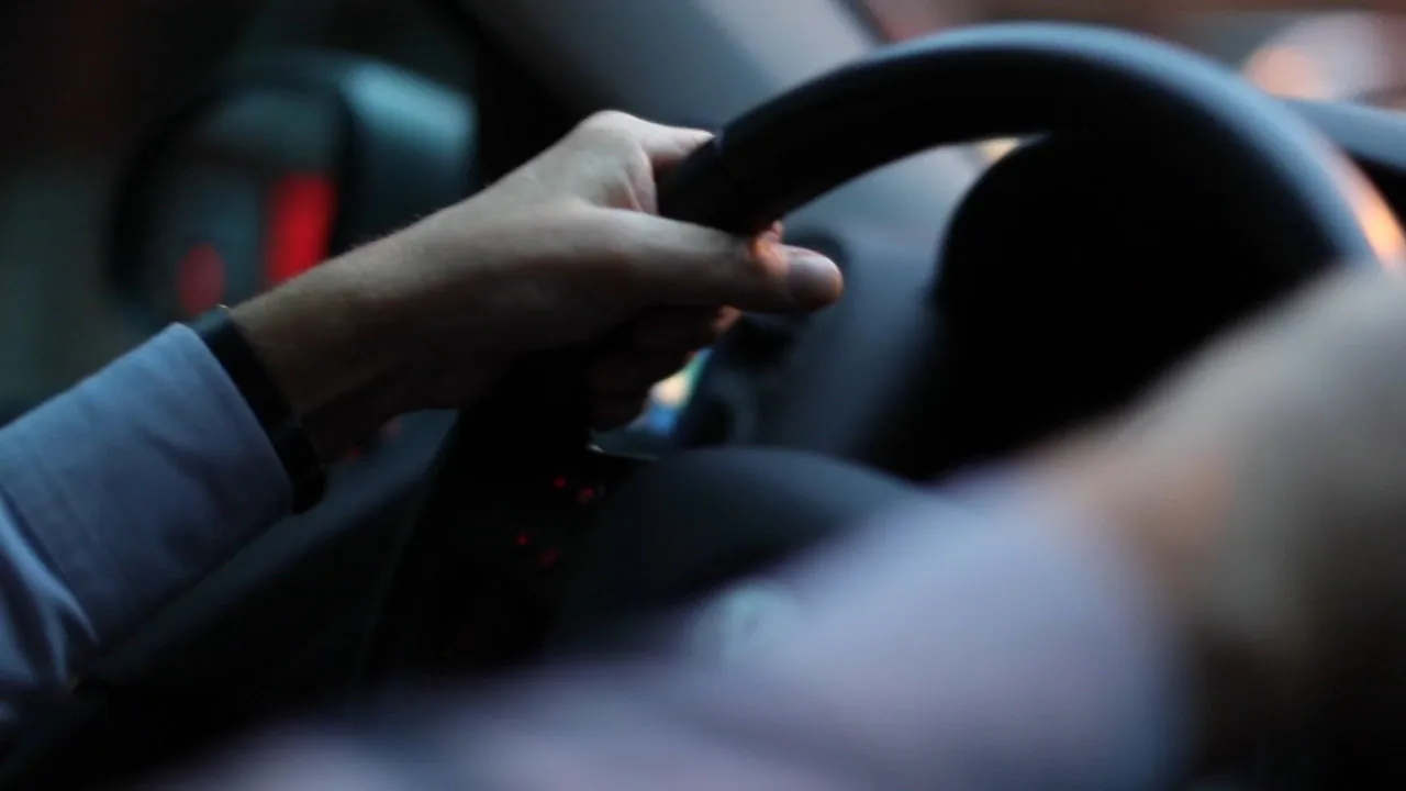 Mano che interagisce con il cambio o i comandi interni di un'auto